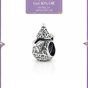 Puede incluir: Un charm de color plateado con un diseño ornamentado, que se asemeja a una tetera. El charm tiene detalles intrincados y un pequeño asa. La imagen también incluye el texto "Buy 2 Items Get 10% Off Or Buy 3+ And Get 20% Off".