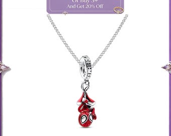 Pode incluir: Um colar de corrente prateada com um pingente de uma cabeça de personagem vermelha e azul com grandes olhos brancos. O pingente está suspenso por uma argola prateada gravada com o texto SPIDER-MAN. Uma placa retangular roxa acima diz Buy 2 Items Get 10% Off Or Buy 3+ And Get 20% Off.