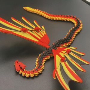 May include: A colorful, articulated dragon figurine with red, yellow, and black accents. The dragon has detailed wings and a segmented body, creating a striking visual effect. The wings are red and yellow with black accents.