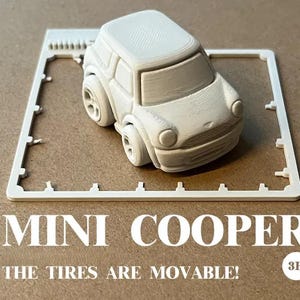 Op de afbeelding: Een wit 3D-geprint Mini Cooper speelgoedauto met beweegbare banden, op een wit frame. De tekst "MINI COOPER" en "THE TIRES ARE MOVABLE!" staan eronder afgedrukt.