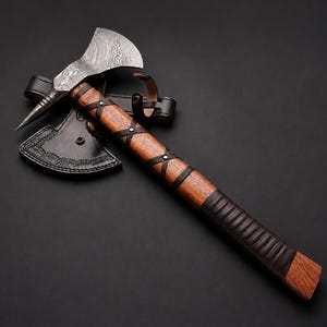 May include: A hand axe with a patterned Damascus steel blade and a pointed poll. The wooden handle is wrapped in dark leather strips secured with metal rivets, and the axe head is partially covered by a black leather sheath with decorative stitching.