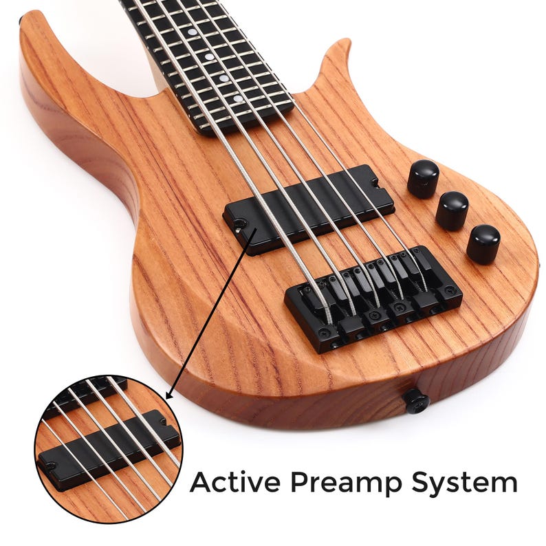 K&ouml;nnte beinhalten: Nahaufnahme einer Bassgitarre aus Holz mit nat&uuml;rlichem Finish. Das Instrument verf&uuml;gt &uuml;ber schwarze Hardware, einschlie&szlig;lich Steg, Tonabnehmern und Kn&ouml;pfen. Der Text "Active Preamp System" ist sichtbar.