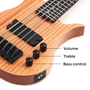K&ouml;nnte beinhalten: Nahaufnahme einer h&ouml;lzernen Bassgitarre mit schwarzer Hardware. Die Gitarre hat vier Saiten, schwarze Regler mit der Aufschrift "Volume", "Treble" und "Bass control" sowie einen schwarzen Tonabnehmer.
