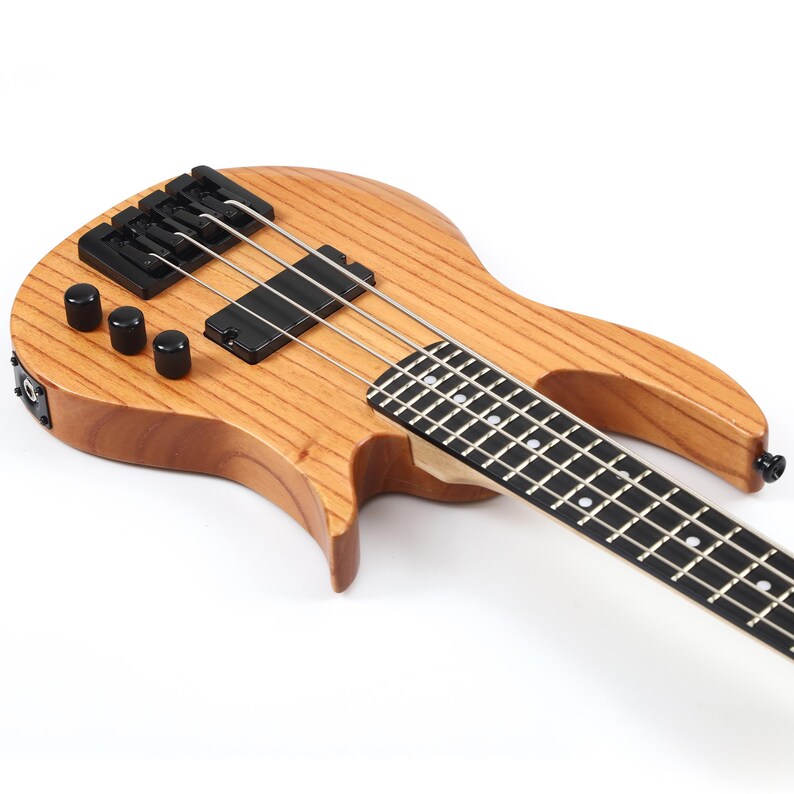 Peut inclure: Une basse de couleur marron clair avec des m&eacute;caniques, un chevalet et des micros noirs. La touche est noire avec des incrustations blanches. L'instrument a quatre cordes et une finition naturelle en grain de bois.