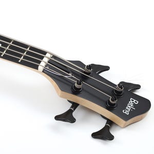 Peut inclure: Gros plan sur une t&ecirc;te de basse Batking noire. La t&ecirc;te comporte quatre chevilles d'accord, des cordes et le nom de la marque en blanc. Le manche est en bois clair et la t&ecirc;te est noire.