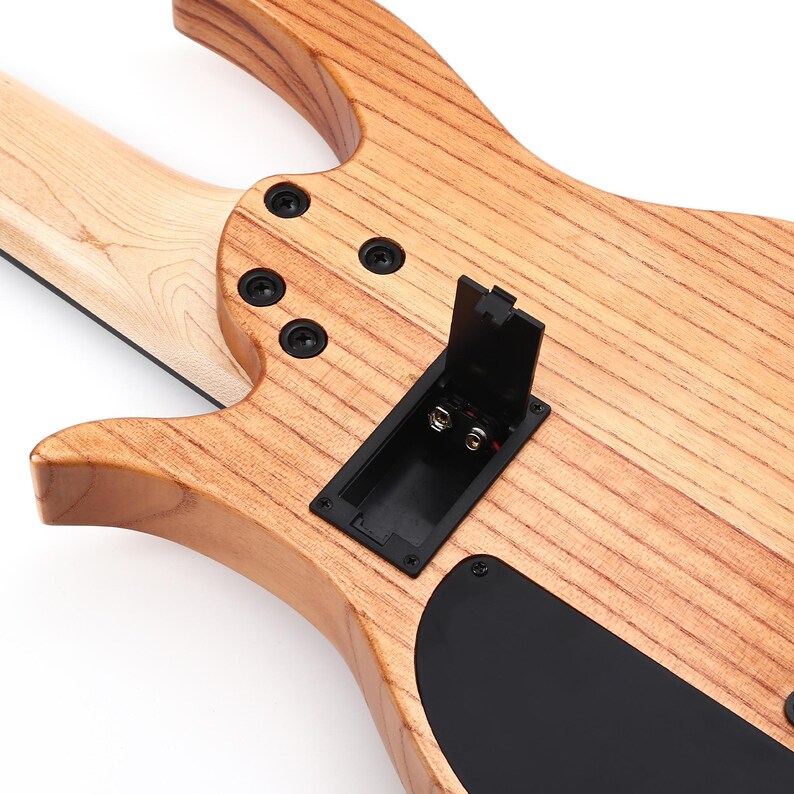 K&ouml;nnte beinhalten: Nahaufnahme der R&uuml;ckseite einer elektrischen Bassgitarre aus Holz. Der Korpus hat eine nat&uuml;rliche Holzmaserung mit schwarzer Hardware, einschlie&szlig;lich Schrauben und einem Batteriefach. Der Hals ist helles Holz.