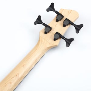 Peut inclure: Gros plan sur la t&ecirc;te et le manche d'une basse. La t&ecirc;te est en bois clair avec quatre m&eacute;caniques noires. Le manche est &eacute;galement en bois clair, avec une bande sombre &agrave; l'arri&egrave;re.