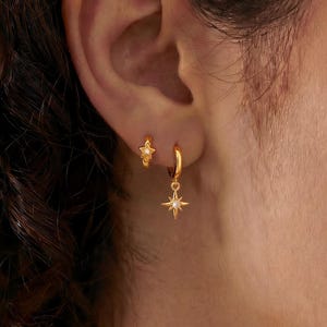 May include: A set of three ceramic mugs with a speckled, matte finish. The mugs are in shades of cream, light gray, and dark gray. Each mug has a simple, modern design and a rounded handle.