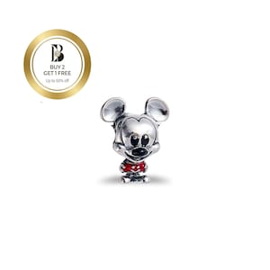 May include: A silver-colored Mickey Mouse charm with a red shirt and black eyes and nose. The charm has a classic Mickey Mouse design and is likely made of metal. The charm is on a white background.