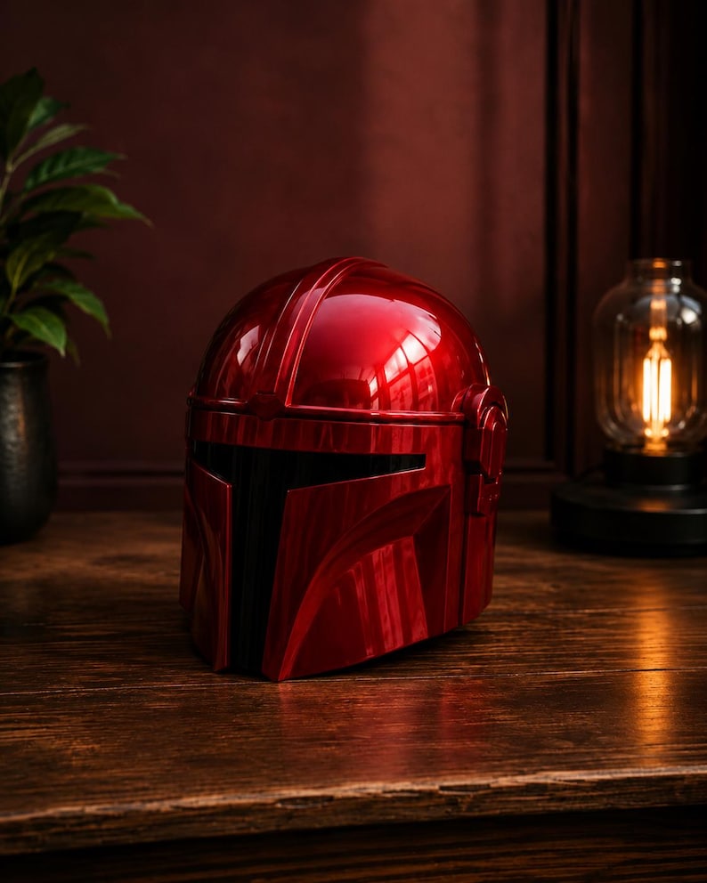 May include: A glossy, metallic red helmet featuring a T-shaped visor design with a black faceplate. The helmet has a smooth, rounded dome and a structured, angular front section, reflecting light across its polished, vibrant crimson surface.