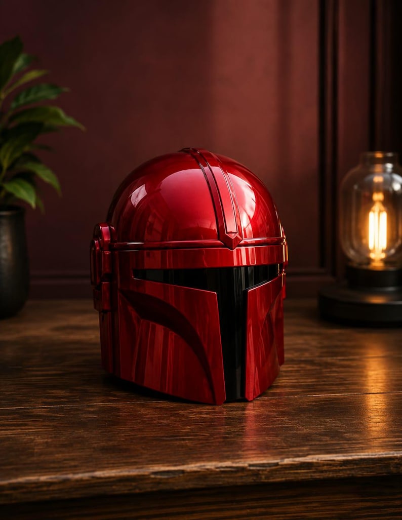 May include: A glossy, metallic red helmet featuring a T-shaped black visor and a smooth, rounded dome design. The helmet has a prominent central ridge running from the top to the brow, with structured side panels and a sleek, reflective finish.