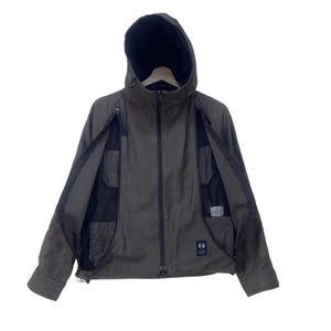 May include: An olive green hooded jacket featuring a central zipper closure, long sleeves, and two large vertical zippered openings on the front chest area that reveal black mesh panels and internal pockets. A small rectangular patch is on the lower right.