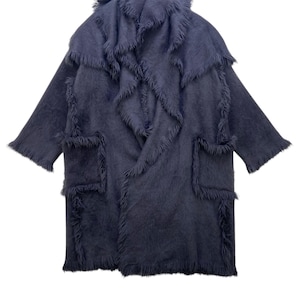 May include: A long, dark blue coat with a distinctive, textured design. The coat has a layered construction with fringed edges and pockets. The overall style is soft and flowing, suitable for cooler weather. The coat's colour is a deep, muted blue.