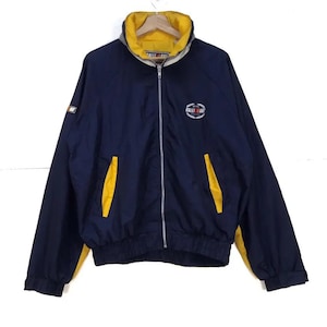 May include: Navy blue and yellow zip-up jacket with a yellow collar and accents. The jacket features the text "RALLI ART" on the chest and a small logo on the sleeve. The jacket has two front pockets and a ribbed hem and cuffs.