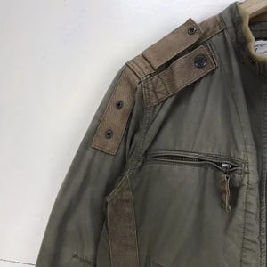 Puede incluir: Chaqueta verde oliva con parches y detalles de hombros en espiga marr&oacute;n. Cuenta con cierre de cremallera y detalles de botones. Dise&ntilde;o cl&aacute;sico de inspiraci&oacute;n militar.