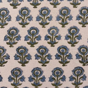 May include: Close-up of a fabric with a repeating floral pattern. The design features blue flowers with green stems and leaves on a cream-colored background. The fabric has a textured appearance.