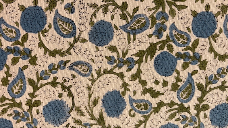 May include: Close-up of a fabric with a repeating floral pattern. The design features blue, green, and white elements. Blue flowers and paisley shapes are interspersed with green vines and leaves on a cream background.