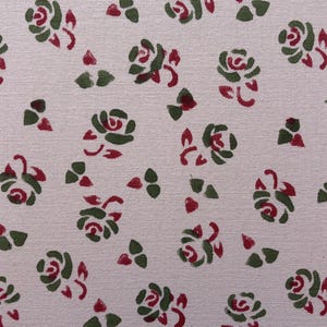 May include: A repeating pattern of stylized roses and leaves in red and green on a light beige background. The floral design is evenly spaced across the surface, creating a delicate and classic aesthetic. The roses are depicted in a simplified, illustrative style.
