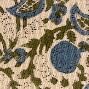 May include: Close-up of a fabric with a repeating floral pattern. The design features blue flowers and green leaves on a cream-colored background. The fabric has a textured appearance.
