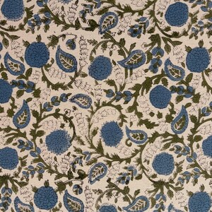May include: Cream-colored fabric with a repeating pattern of blue floral and paisley shapes, connected by green vines and leaves. The design has a hand-blocked print appearance, creating a textured look.