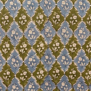May include: A repeating pattern of blue and olive green diamond shapes, each containing a white floral design. The pattern is symmetrical and creates a textured, decorative effect, suitable for textiles or wallpaper.
