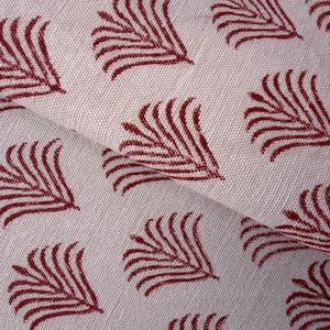 Peut inclure: Gros plan sur un tissu plié avec un motif répétitif de feuilles stylisées de couleur bordeaux. Le tissu a un fond beige clair et un aspect texturé, suggérant un matériau en lin ou en coton. Le motif de feuilles est espacé uniformément.