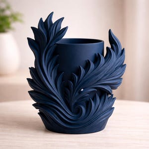 Puede incluir: Un jarrón decorativo azul marino con un diseño detallado en forma de hojas. El jarrón tiene forma cilíndrica con una amplia abertura y está adornado con intrincados patrones arremolinados. El color azul oscuro y el diseño ornamentado le dan un aspecto clásico y elegante.