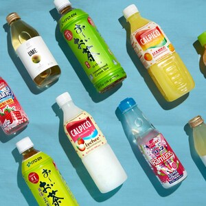 May include: Assortment of bottled beverages, including green tea, mango juice, lychee-flavored drinks, and a clear soda. The bottles have various labels with Japanese text and colorful graphics, set against a light blue background.