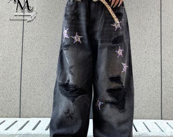 May include: Black denim wide-leg jeans with distressed details and star embellishments. The jeans feature ripped sections and are adorned with sequined star designs. A leopard print belt is worn with the jeans.