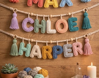 以下が含まれることがあります： MAX、CHLOE、HARPERと綴られたかぎ針編みの文字が吊り下げられた3本の水平なマクラメロープ。各ロープには木製のビーズと両端にカラフルな糸のタッセルが付いています。下には、毛糸玉、多肉植物、キャンドルが入った編みかごが置かれています。