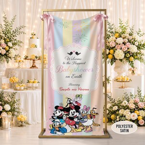 May include: A vertical polyester satin banner featuring a pastel striped background with fireworks, displaying the text Welcome to the Happiest Babyshower on Earth Honoring Sophia and Nathan, with Mickey, Minnie, Donald, Daisy, Goofy, and Pluto.