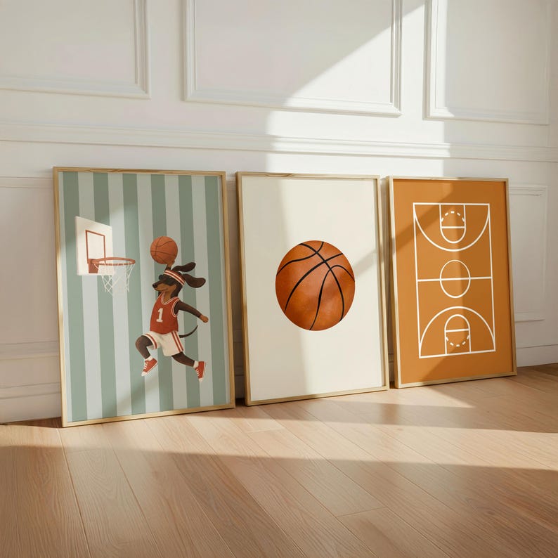Puede incluir: Tres l&aacute;minas de pared enmarcadas con tem&aacute;tica de baloncesto. La primera muestra a un perro salchicha con camiseta roja y blanca saltando hacia una canasta. La segunda muestra un bal&oacute;n centrado sobre fondo crema. La tercera muestra un diagrama.