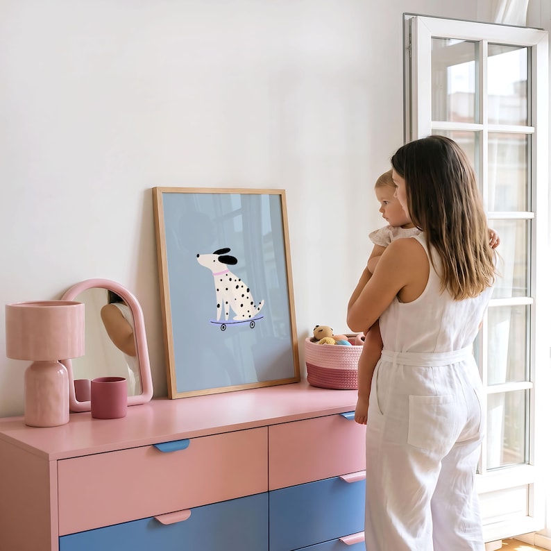 Puede incluir: Una l&aacute;mina enmarcada con un dibujo de un perro d&aacute;lmata con manchas negras y collar rosa sobre un monopat&iacute;n azul con fondo azul claro. La l&aacute;mina est&aacute; sobre una c&oacute;moda rosa y azul junto a una l&aacute;mpara y un espejo de color rosa.