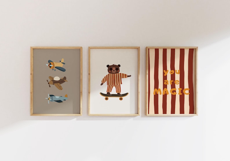 Puede incluir: Tres l&aacute;minas decorativas enmarcadas. La de la izquierda muestra tres aviones peque&ntilde;os en azul, marr&oacute;n y azul claro. La central presenta un oso marr&oacute;n en pijama de rayas sobre un monopat&iacute;n. La de la derecha tiene rayas rojas y el texto you are MAGIC.