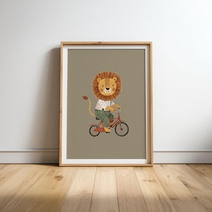 Puede incluir: Una l&aacute;mina de arte enmarcada que muestra a un le&oacute;n marr&oacute;n con una gran melena, vestido con una camisa blanca estampada y pantalones verdes, montando una bicicleta roja. La ilustraci&oacute;n est&aacute; sobre un fondo topo en un marco de madera.