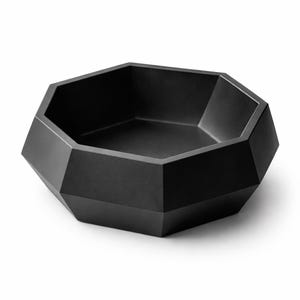 Op de afbeelding: Een matzwarte, geometrische kom met een facetvormige buitenkant. De kom heeft een achthoekige vorm met een platte bodem en een gladde binnenkant. De kom is gemaakt van een stevig materiaal en is geschikt om te serveren of tentoon te stellen. Diameter: ongeveer 25 cm.