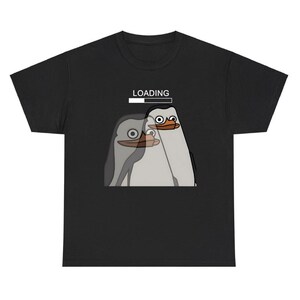 May include: Black t-shirt featuring a cartoon penguin design. The graphic shows two penguins with surprised expressions, and the word "LOADING" above them with a progress bar. The penguins are gray and white.