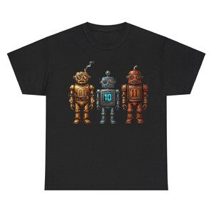 Puede incluir: Camiseta negra con tres ilustraciones de robots vintage. Los robots son de color oro, plata y cobre, cada uno con un número: 01, 10 y 11. El robot dorado tiene una chimenea humeante.