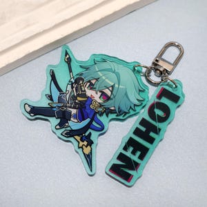 May include: An acrylic keychain featuring a stylized anime character with teal hair and heterochromatic eyes, wearing a blue and black outfit. A secondary rectangular acrylic charm attached by a metal ring displays the text LOHEN in black letters.