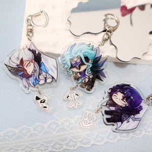 Puede incluir: Tres llaveros acrílicos con personajes de estilo anime con diseños detallados. Cada llavero tiene un anillo plateado y un pequeño dije con un símbolo. Los personajes tienen peinados y atuendos únicos, con una variedad de colores.