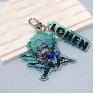 May include: An acrylic keychain featuring a chibi-style character with teal hair, wearing a blue and black outfit, and holding a spear. A separate rectangular acrylic charm attached to the silver clasp displays the text LOHEN in black letters.