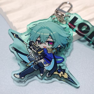 May include: A translucent light blue acrylic keychain featuring a chibi-style character with teal hair, purple eyes, and a blue outfit, holding a spear-like weapon. The charm includes a silver metal lobster clasp and a partial tag with black text.