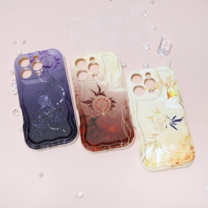 May include: Three smartphone cases with detailed designs. The cases feature a gradient of colours, including purple, red, and yellow, with intricate illustrations. The cases are made of a glossy material and are designed to fit a smartphone.