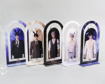 May include: Five acrylic display stands featuring male figures in various outfits. Each stand has an arched top and a base with a name printed on it. The stands are in different colors, including blue, black, and white.
