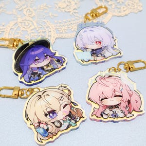 May include: Four acrylic keyrings featuring anime-style characters with gold-coloured clasps. The characters have various hair colours, including purple, white, and pink. Each keyring has a unique design and is suitable for attaching to keys or bags.