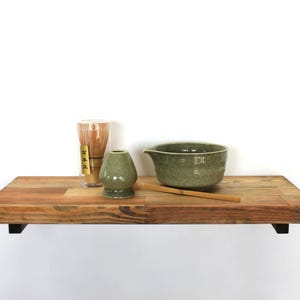 May include: A set of three ceramic mugs with a speckled, matte finish in cream, light grey, and dark grey. Each mug has a simple, minimalist design, suitable for coffee or tea.