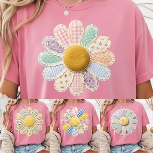 May include: Pink t-shirt featuring a large, appliqued daisy design. The daisy has a textured yellow center and petals in various pastel patterns, including gingham, polka dots, and floral prints. The shirt is a casual, short-sleeved style.