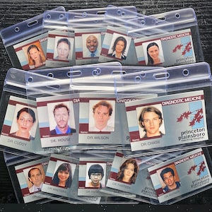 May include: A collection of clear plastic ID badge holders, each containing a photo and name tag. The tags display the words "Diagnostic Medicine" and "Princeton Plainsboro Teaching Hospital". The photos are of various people.