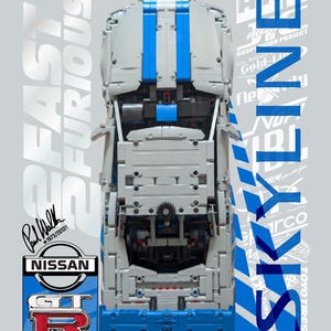 Könnte beinhalten: Eine Draufsicht auf ein graues und blaues LEGO Technic Nissan GT-R Modellauto. Das Design zeigt den Text 2 FAST 2 FURIOUS und SKYLINE, ein Nissan GT-R Logo, ein Florida-Nummernschild mit der Aufschrift T4U 842 und eine Paul Walker Signatur.