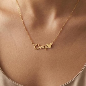May include: A gold-colored necklace with the name "Candy" in a cursive font. A small mouse-shaped design is next to the name. The necklace is worn around the neck.